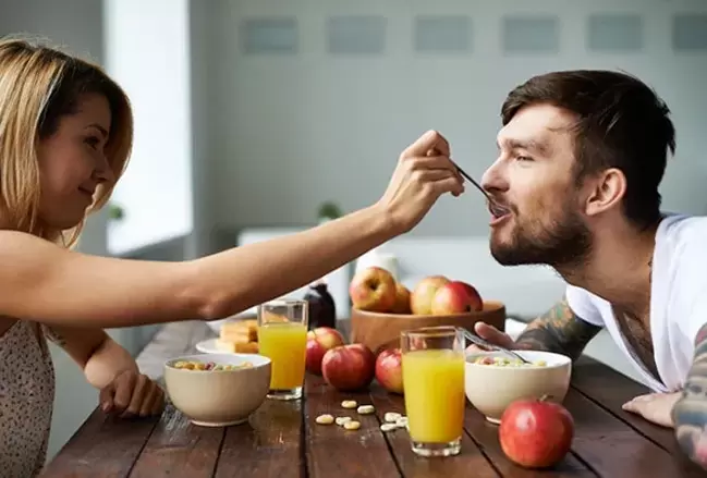 woman feeds man nuts to increase strength